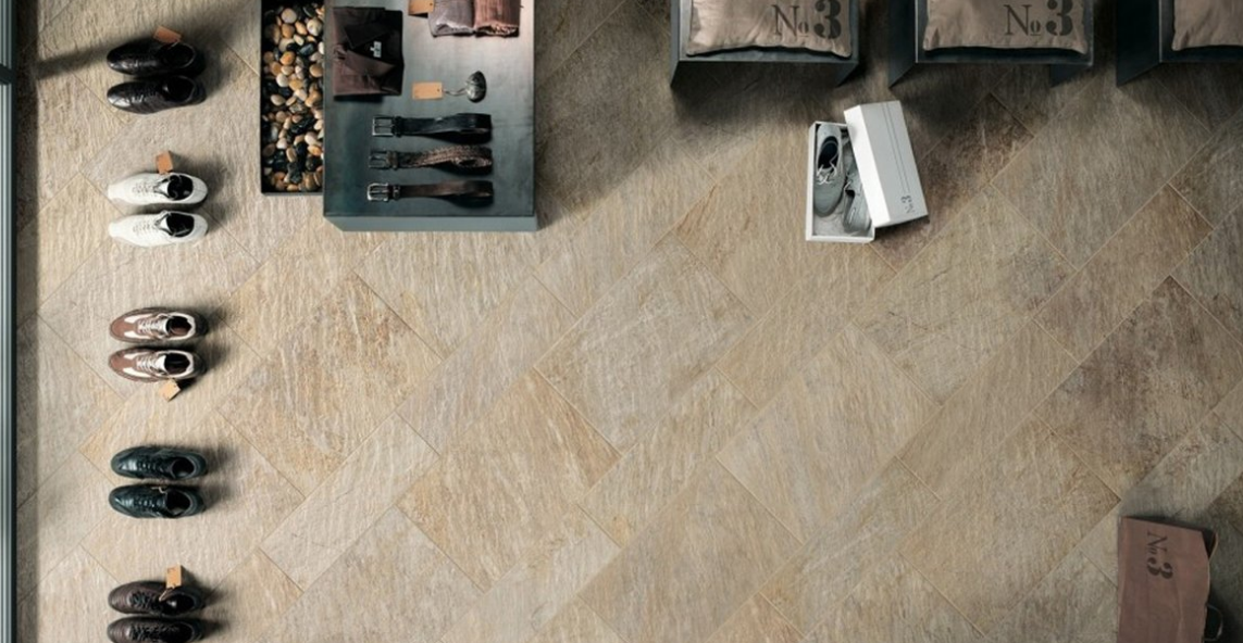 Vue aérienne de chaussures, de portants à vêtements et d'une petite table sur un sol beige, comme un étal de marché.