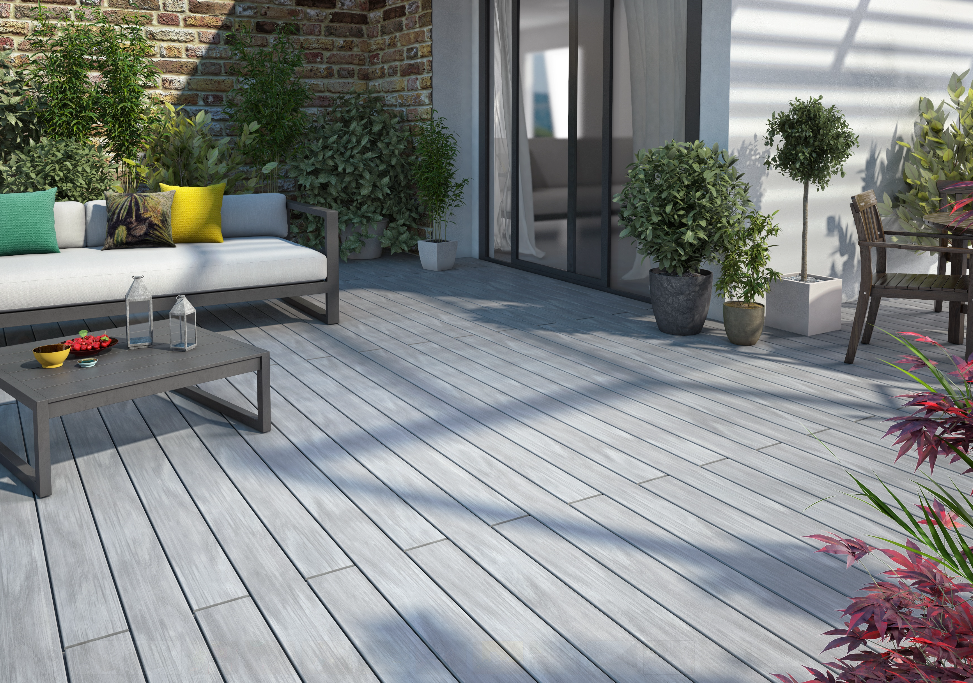 Patio moderne avec terrasse grise, canapé d'extérieur, table basse, plantes en pot et coin repas près d'un mur en briques