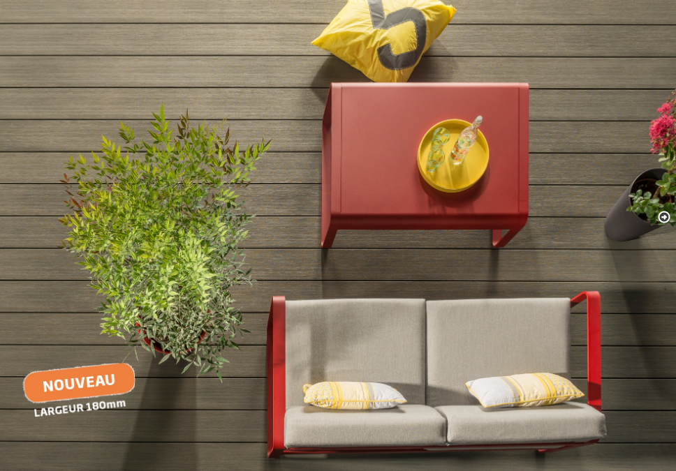 Vue plongeante d'un ensemble de salon de jardin rouge et beige avec table, canapé et plante verte sur une terrasse en bois