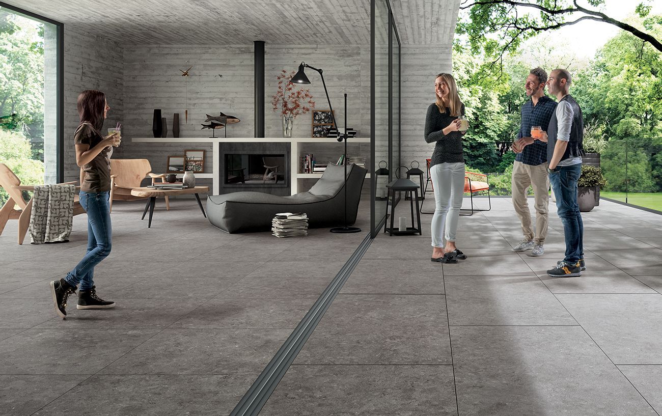 Des personnes se promènent et discutent devant une maison moderne avec terrasse couverte et jardin.