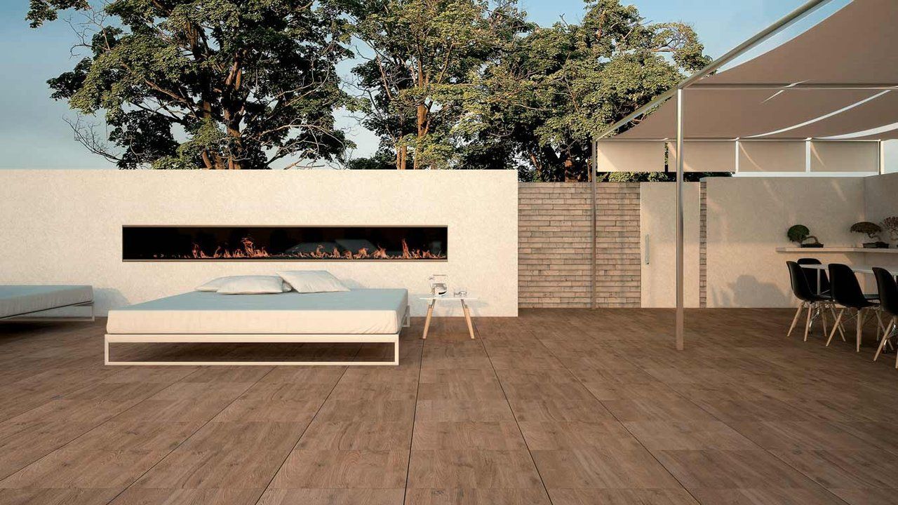 Terrasse moderne avec banc bas, cheminée en briques, terrasse en bois, arbres et chaises longues sous une pergola