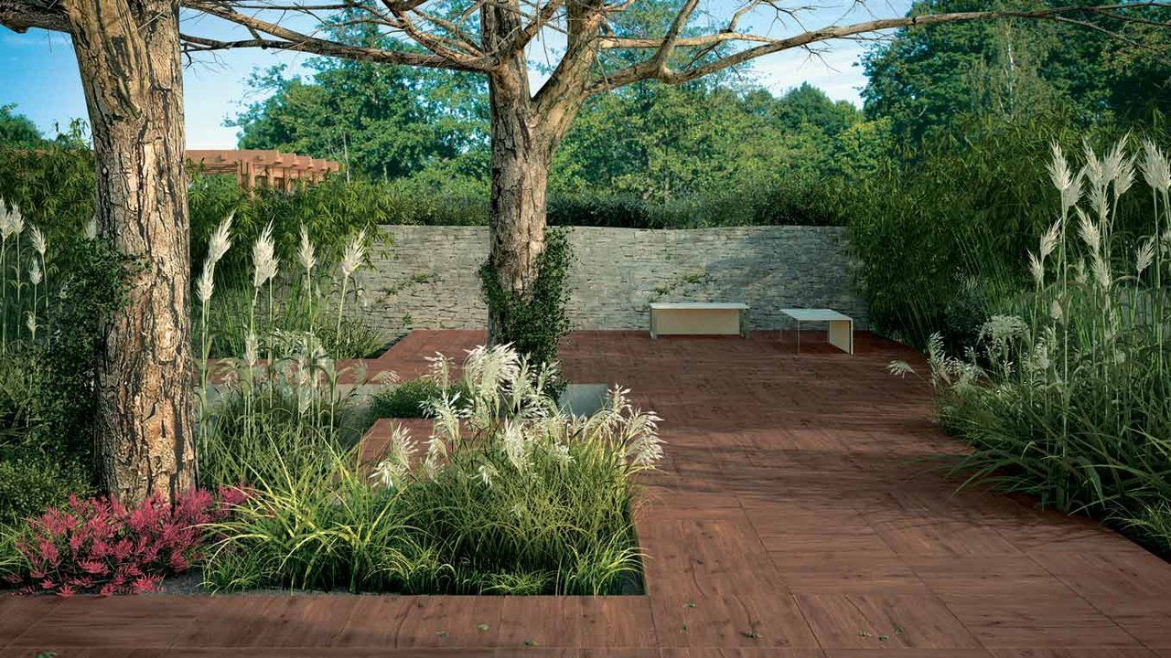 Terrasse en bois avec fleurs en pot et arbres à côté d'un jardin luxuriant et d'un coin salon
