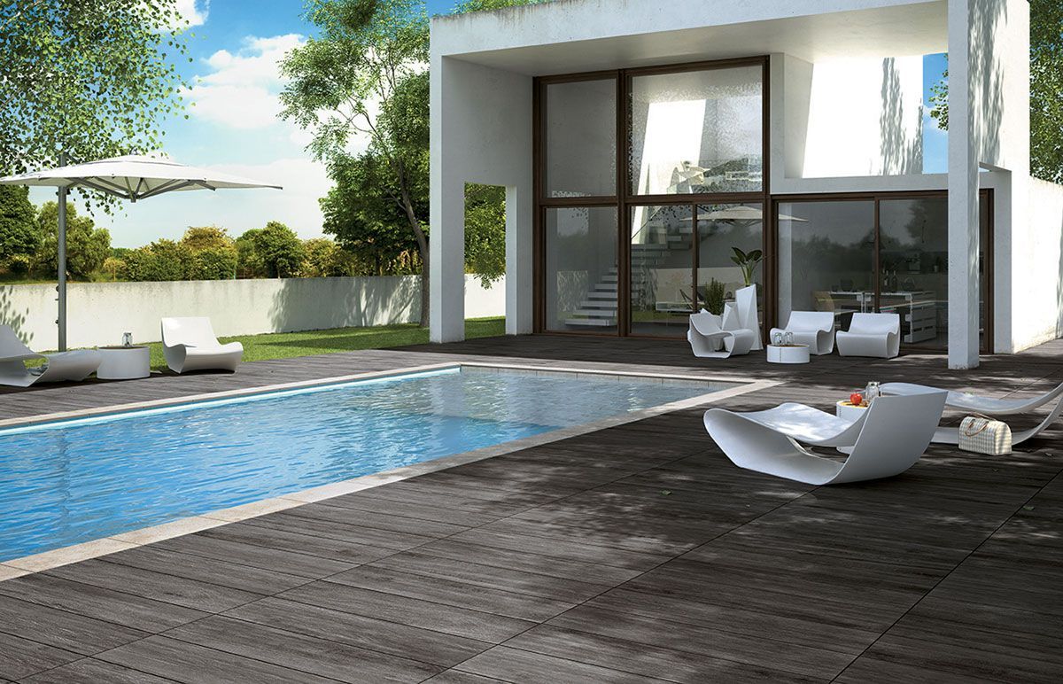 Patio moderne avec piscine, chaises longues et maison aux parois de verre en arrière-plan