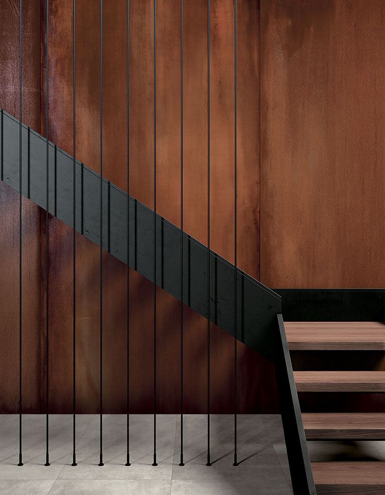 Escalier moderne avec rampe noire contre un mur lambrissé et un sol gris