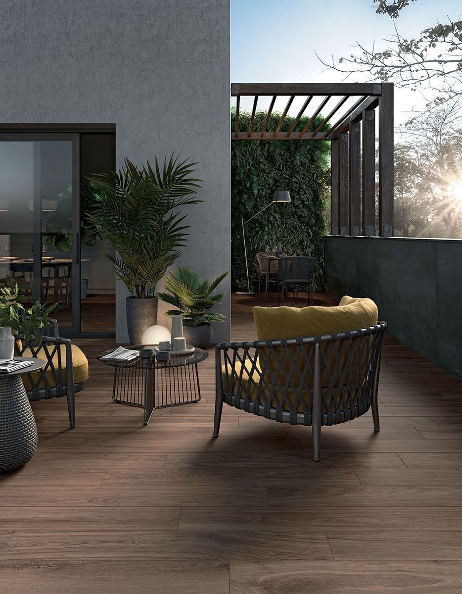 Terrasse moderne sur le toit avec chaises en osier, plantes en pot et pergola au coucher du soleil