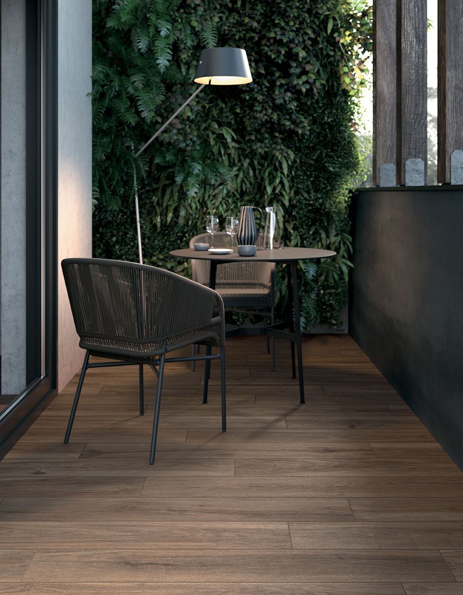 Coin repas moderne sur une terrasse avec deux chaises noires, une petite table ronde et un mur végétal.