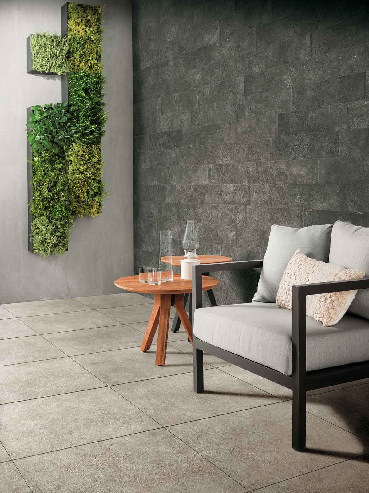 Salon moderne avec canapé gris, table basse en bois et plante verte murale verticale sur mur en béton