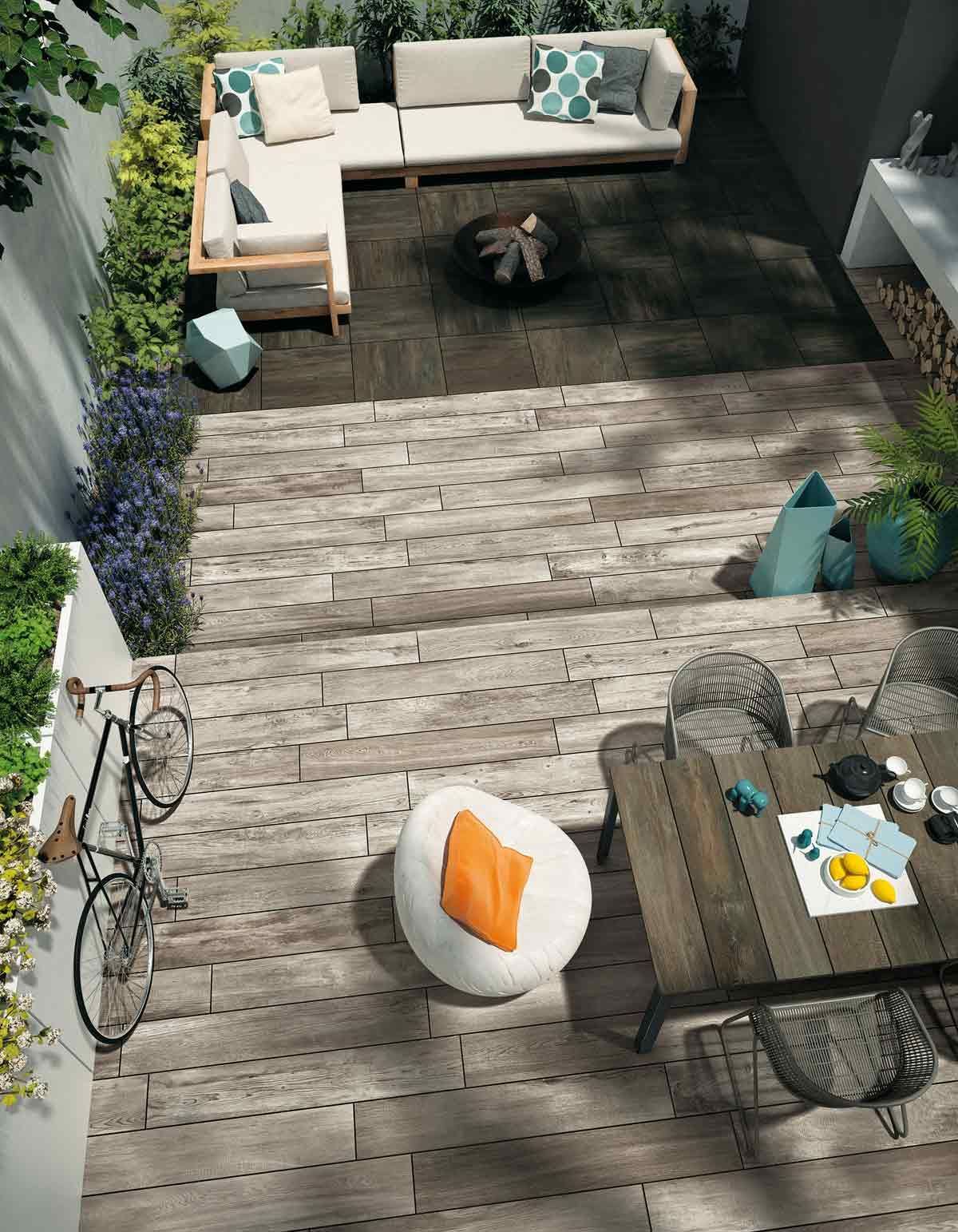 Terrasse avec canapé d'angle, fauteuils, table basse, vélo et balcon donnant sur un jardin