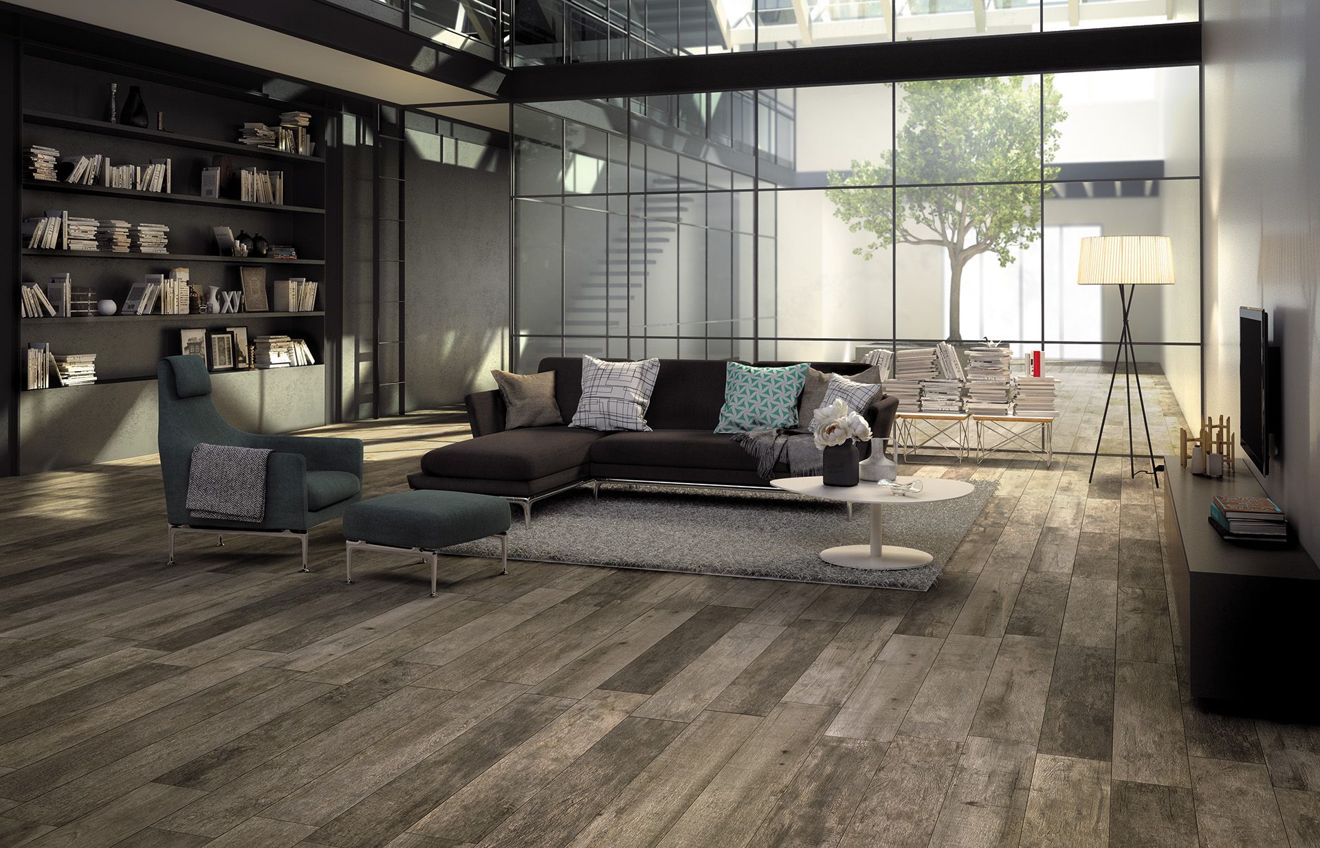Salon moderne avec canapé d'angle gris, étagères en bois foncé et grandes fenêtres donnant sur un patio lumineux.