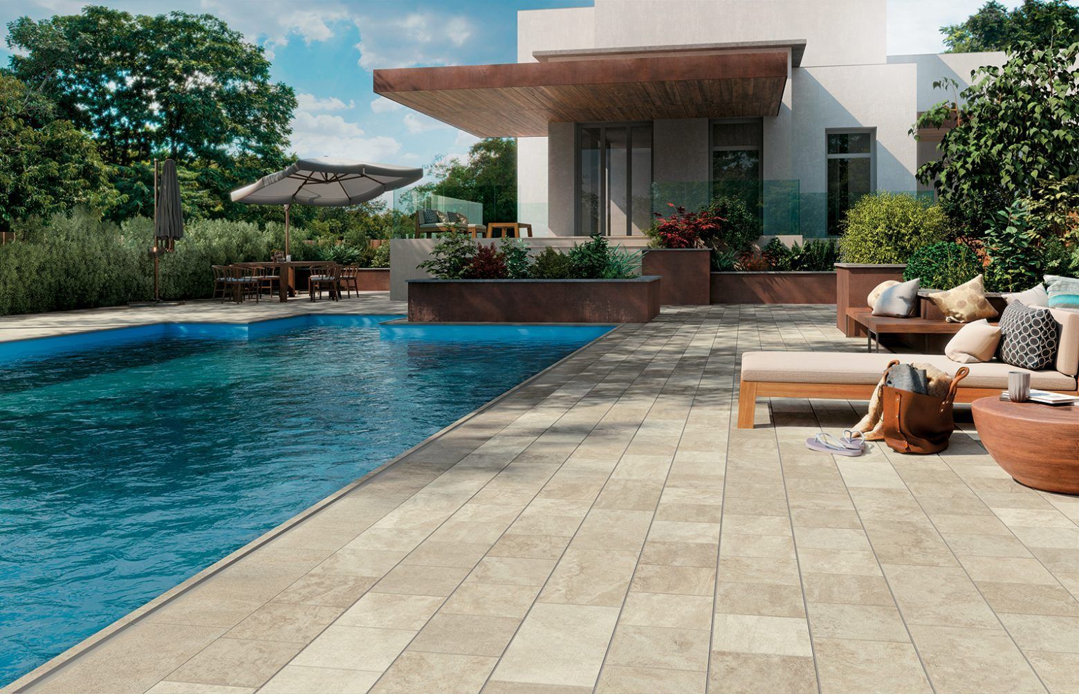 Jardin moderne avec piscine bleue, terrasse en pierre et chaises longues confortables à côté d'une maison blanche.
