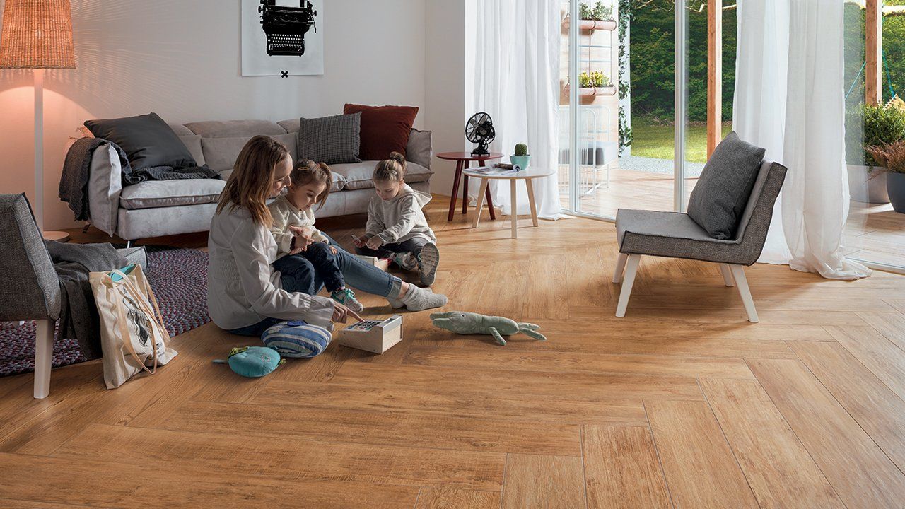 Deux personnes assises sur un parquet dans un salon lumineux, en train de faire un puzzle avec le canapé et les fauteuils à proximité.
