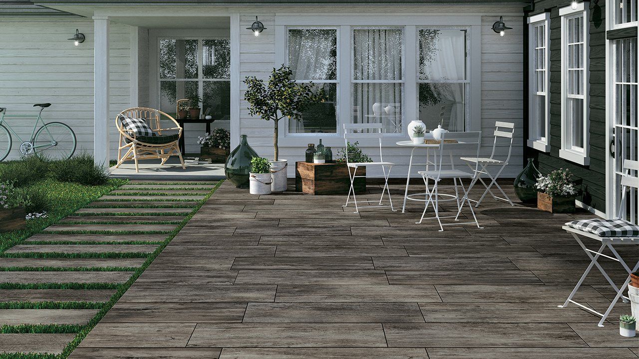Terrasse arrière avec plancher en bois vieilli, table et chaises d'extérieur blanches, plantes en pot et portes coulissantes en verre