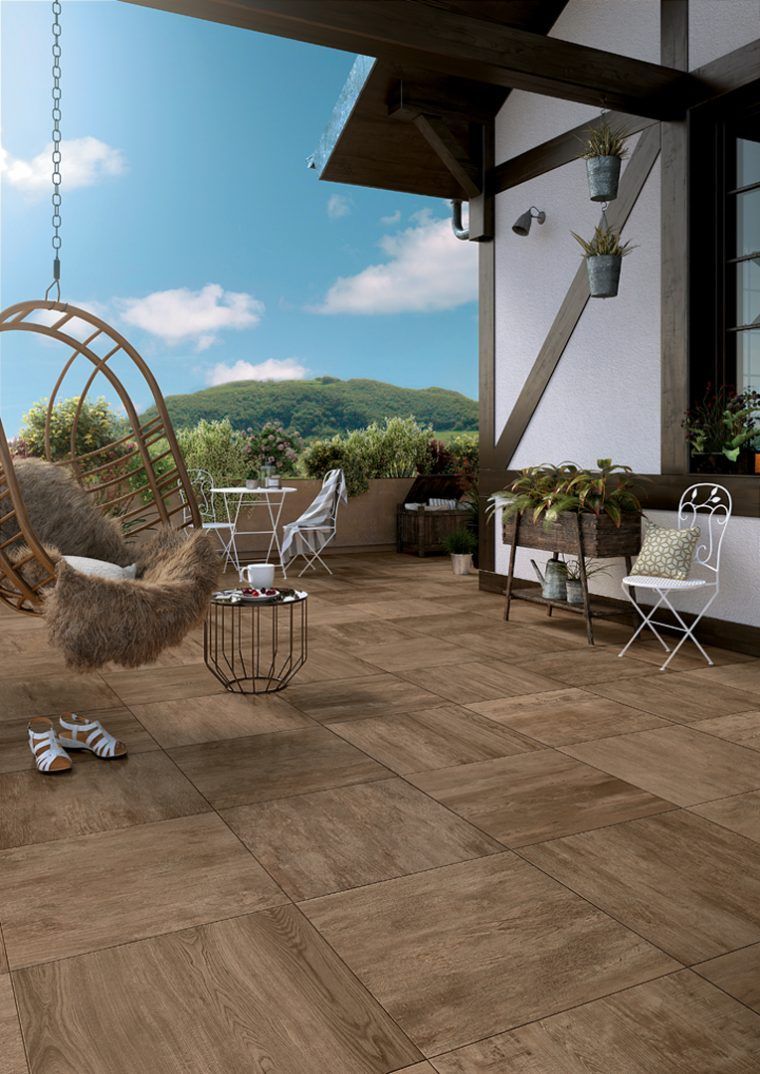 Terrasse avec fauteuil suspendu en forme d'œuf, sièges blancs, plantes en pot et vue sur la montagne sous un toit couvert