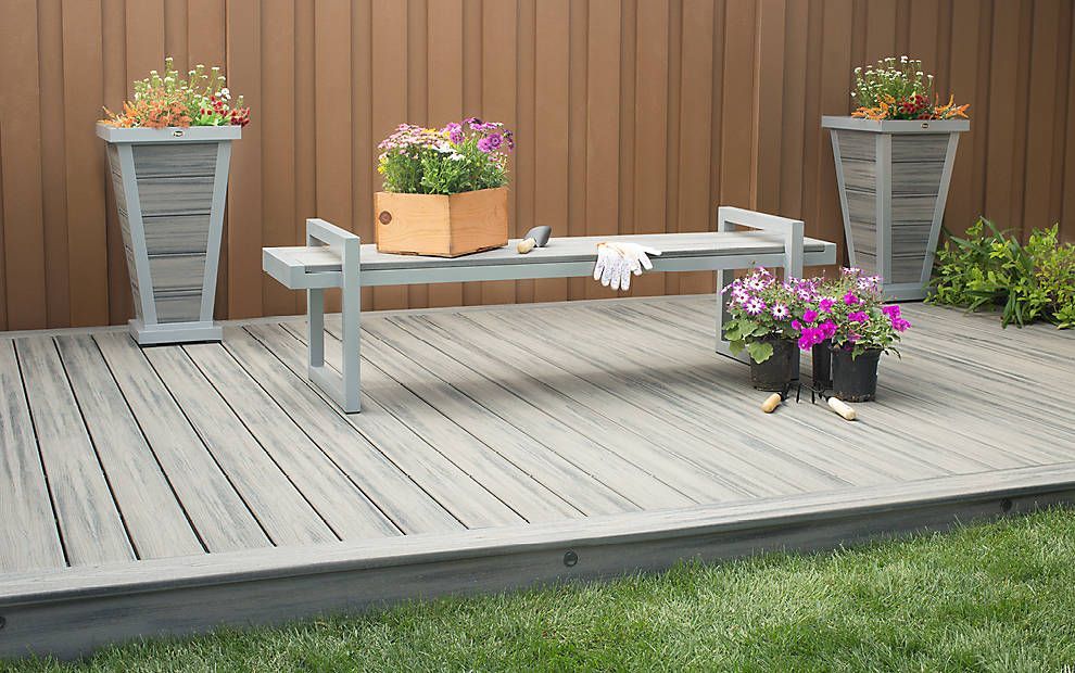 Terrasse avec bancs, fleurs en pot et jardinières sur un patio en bois.
