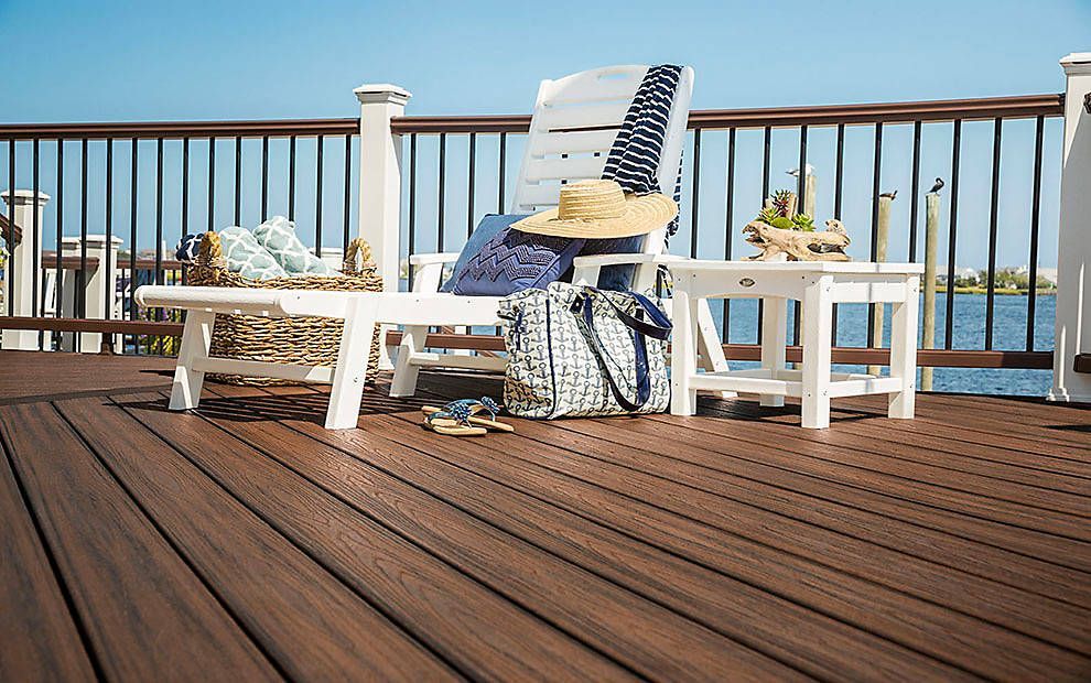 Des chaises Adirondack blanches et une table sur une terrasse en bois surplombant l'océan