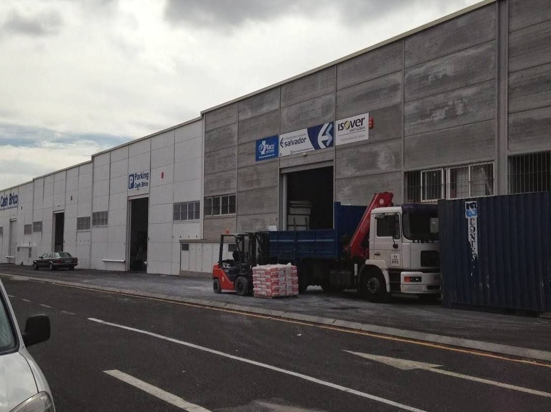 Un camión está estacionado frente a un edificio con una carretilla elevadora delante de él.