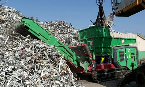 Una gran pila de chatarra está siendo triturada por una máquina.