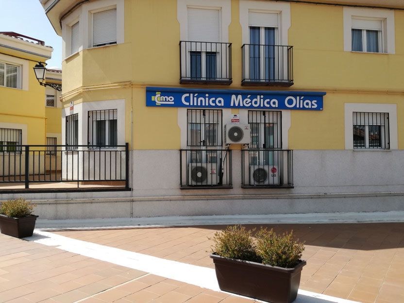 Un edificio amarillo con un cartel azul que dice Clínica Médica Olias.