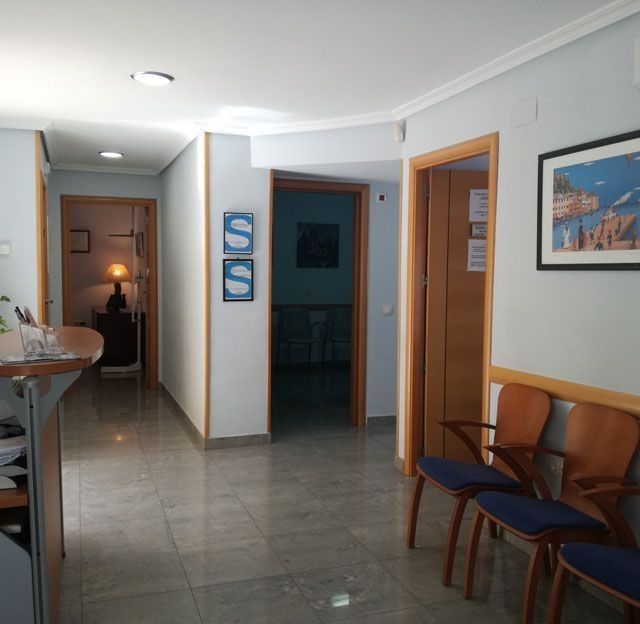 Una sala de espera con sillas y un cuadro en la pared.