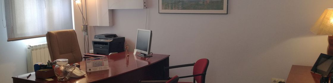 Una habitación con un escritorio y sillas y un cuadro en la pared.