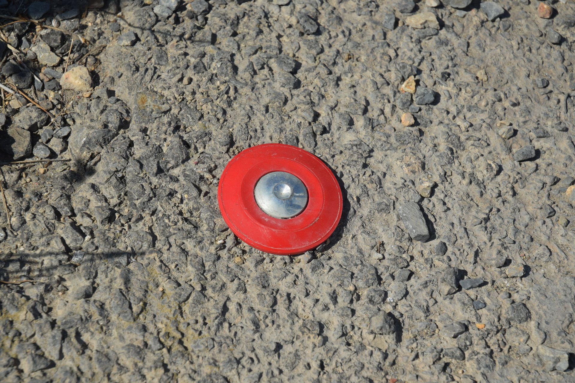 Réflecteur rouge encastré dans l'asphalte.