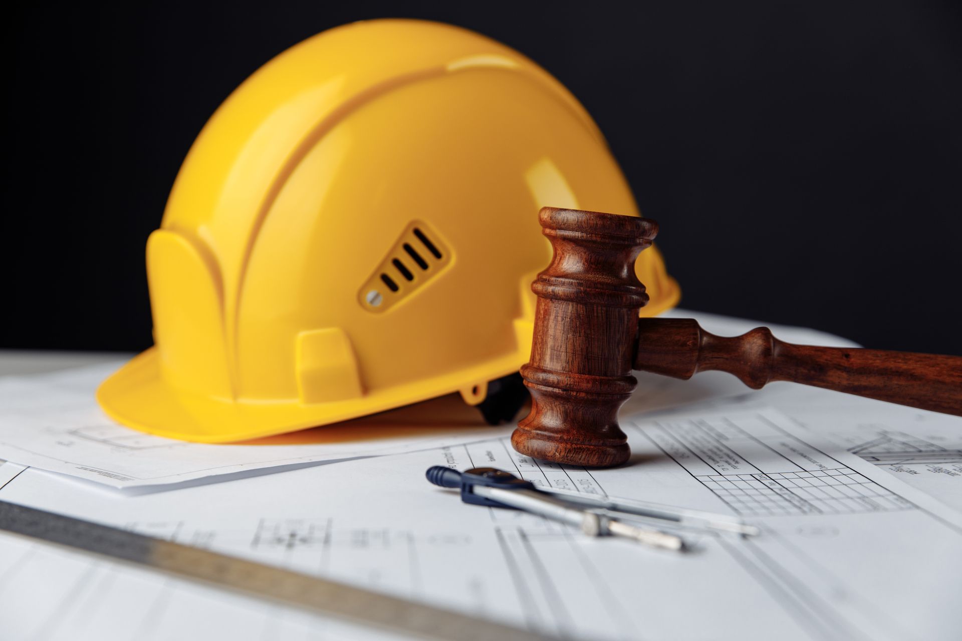 Un casque jaune, un maillet et des plans symbolisant le droit de la construction.