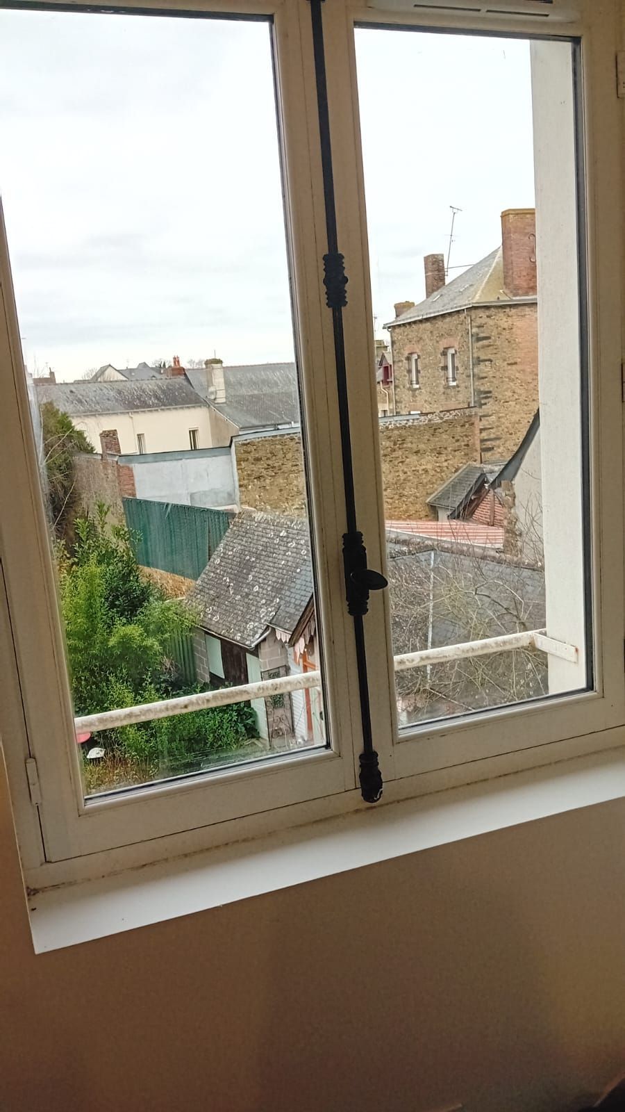 Une fenêtre avec vue sur une ville et un balcon.