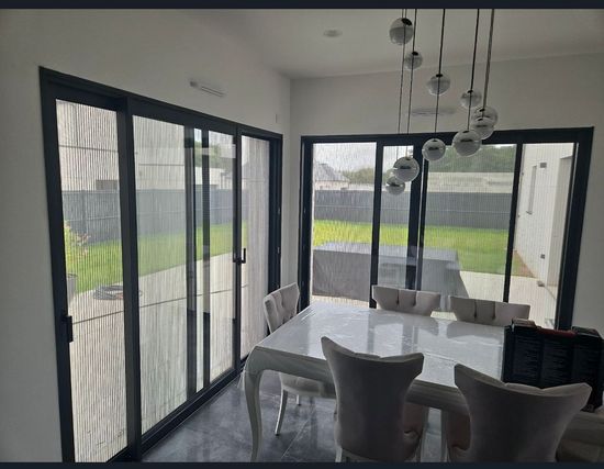 Une salle à manger avec une table et des chaises et des portes coulissantes en verre.
