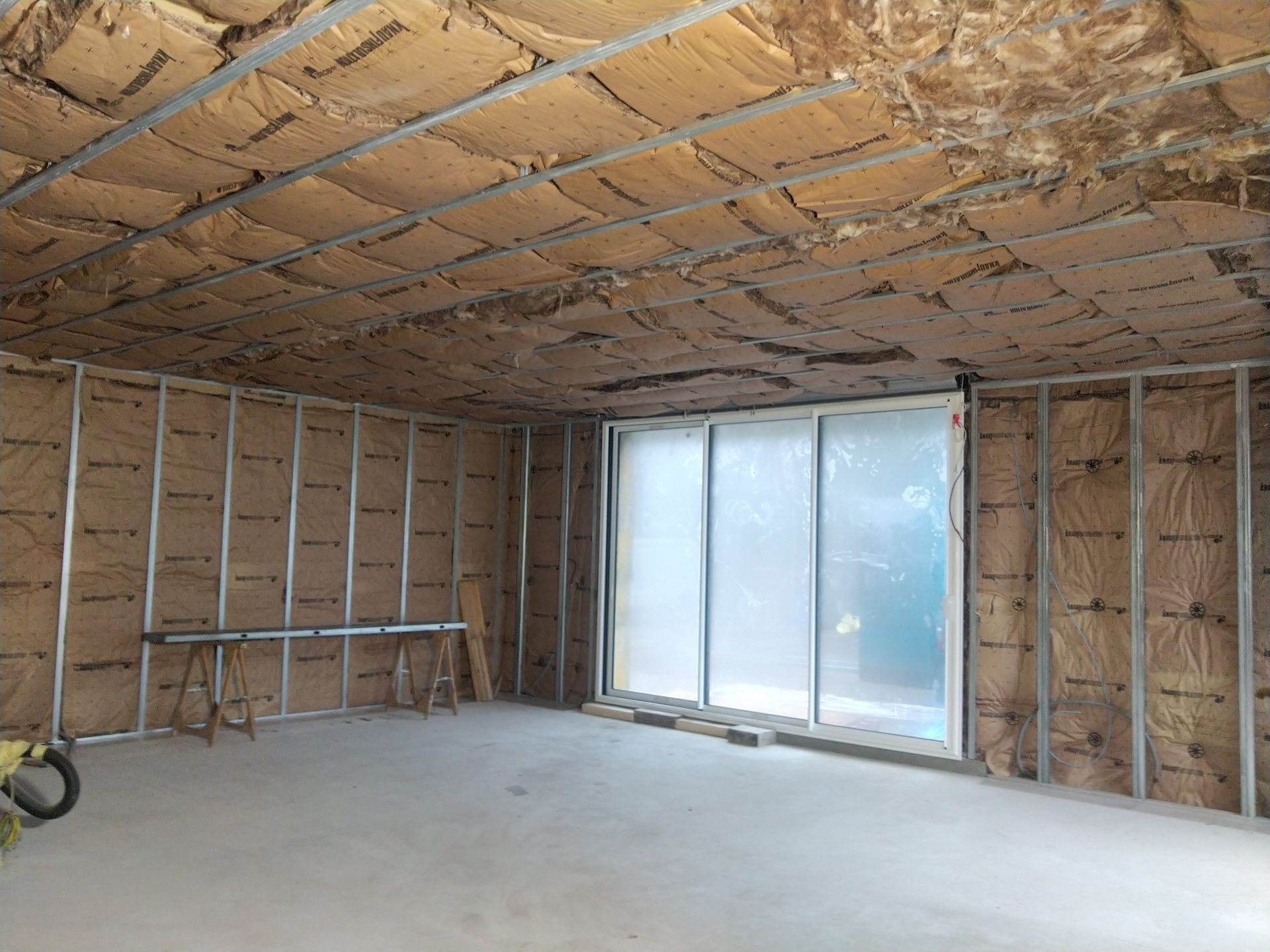 Espace sans plaque de plâtre avec que de l'isolant du sol au plafond et une porte-fenêtre