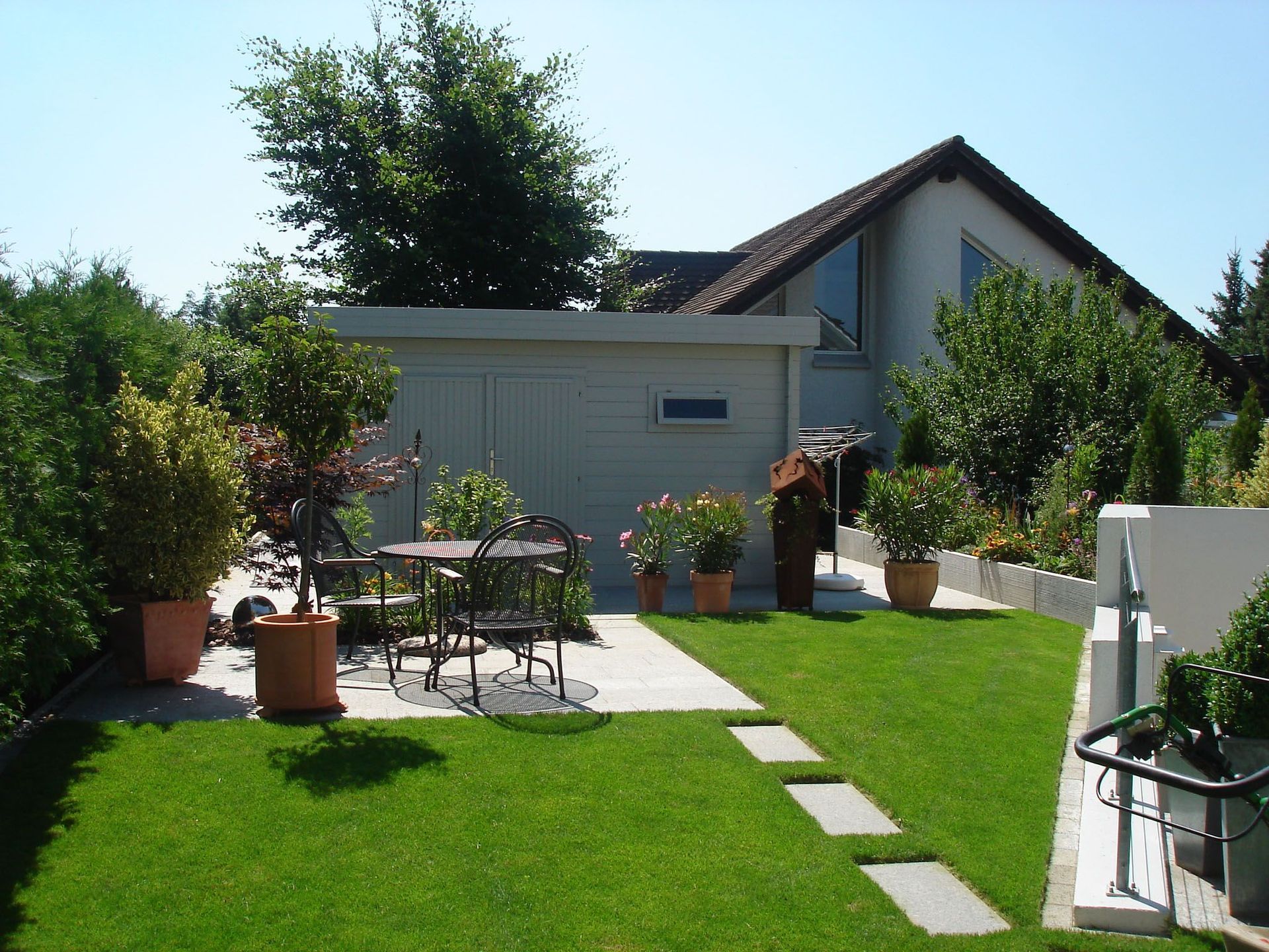 Eine Wiese mit Tisch und Stühlen vor einem Haus
