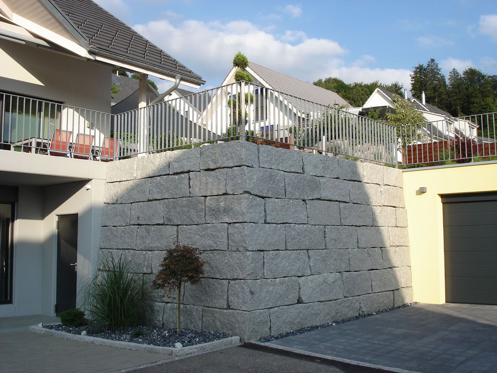 Eine große Steinmauer umgibt eine Garage und ein Haus