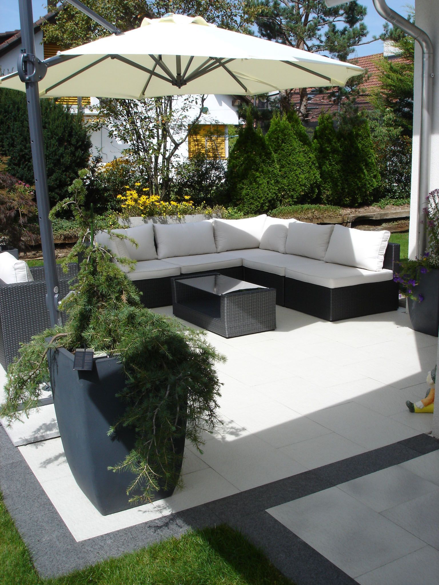 Eine Terrasse mit Sofagarnitur und Sonnenschirm