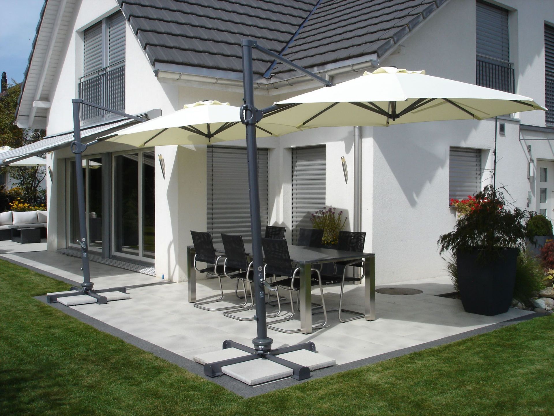 Eine Terrasse mit Sonnenschirmen und einem Tisch und Stühlen vor einem Haus