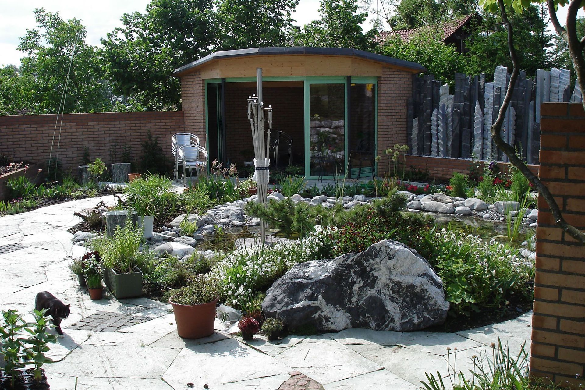 Ein Backsteingebäude mit einem grünen Fenster steht inmitten eines Gartens