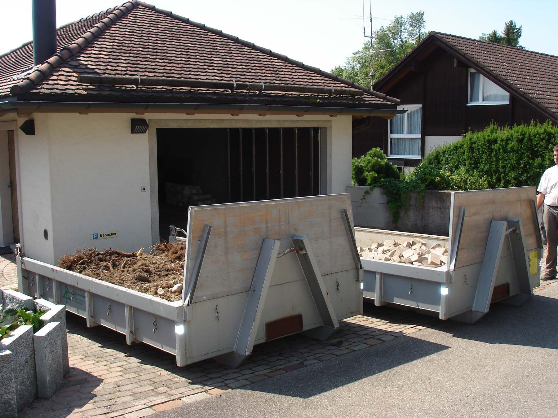 Zwei Müllcontainer stehen vor einem weißen Haus