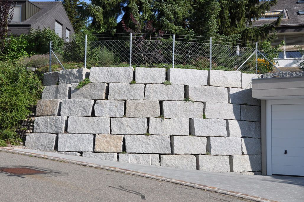 Eine große Steinmauer mit einer Garage im Hintergrund