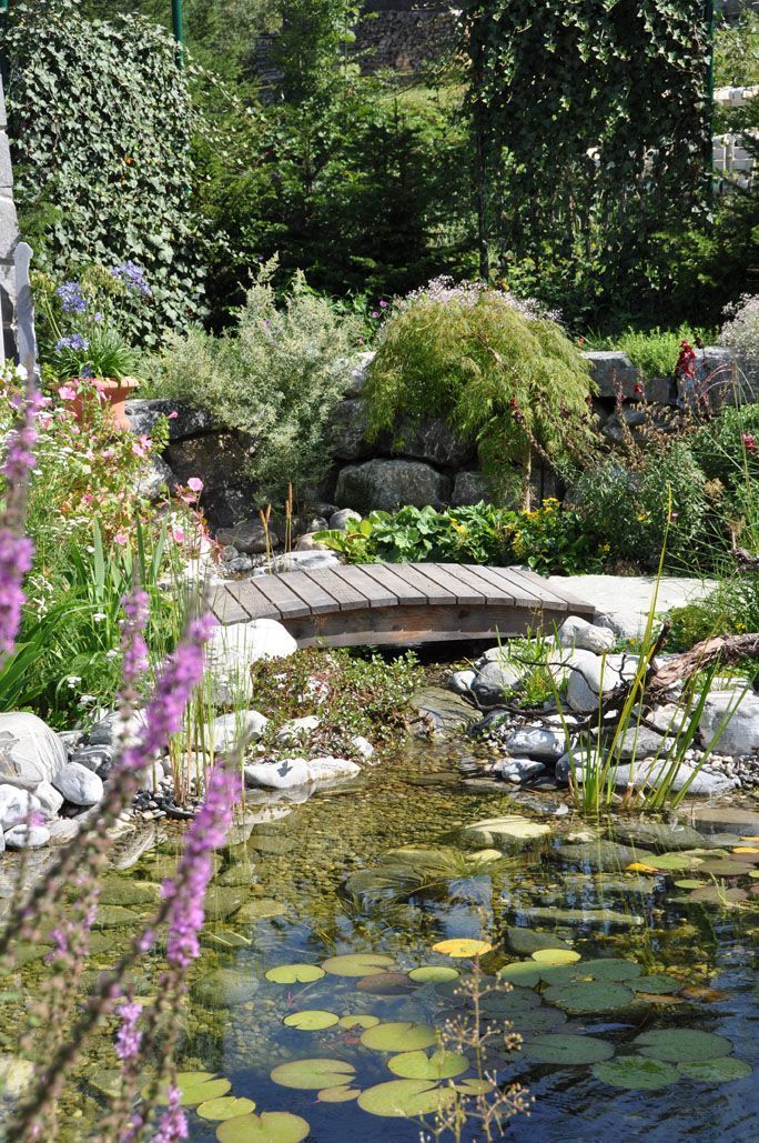 In der Mitte eines Gartens befindet sich eine Brücke über einem Teich.