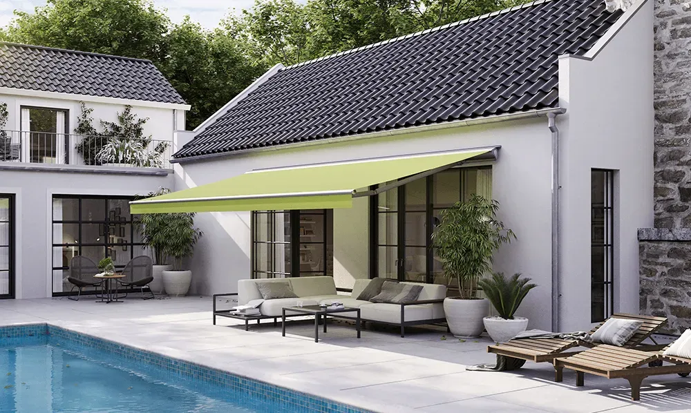 Ein weißes Haus mit einer grünen Markise über einem Swimmingpool.