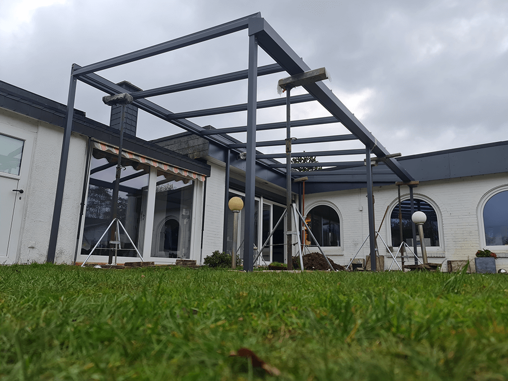 Ein weißes Haus mit einer Pergola davor.