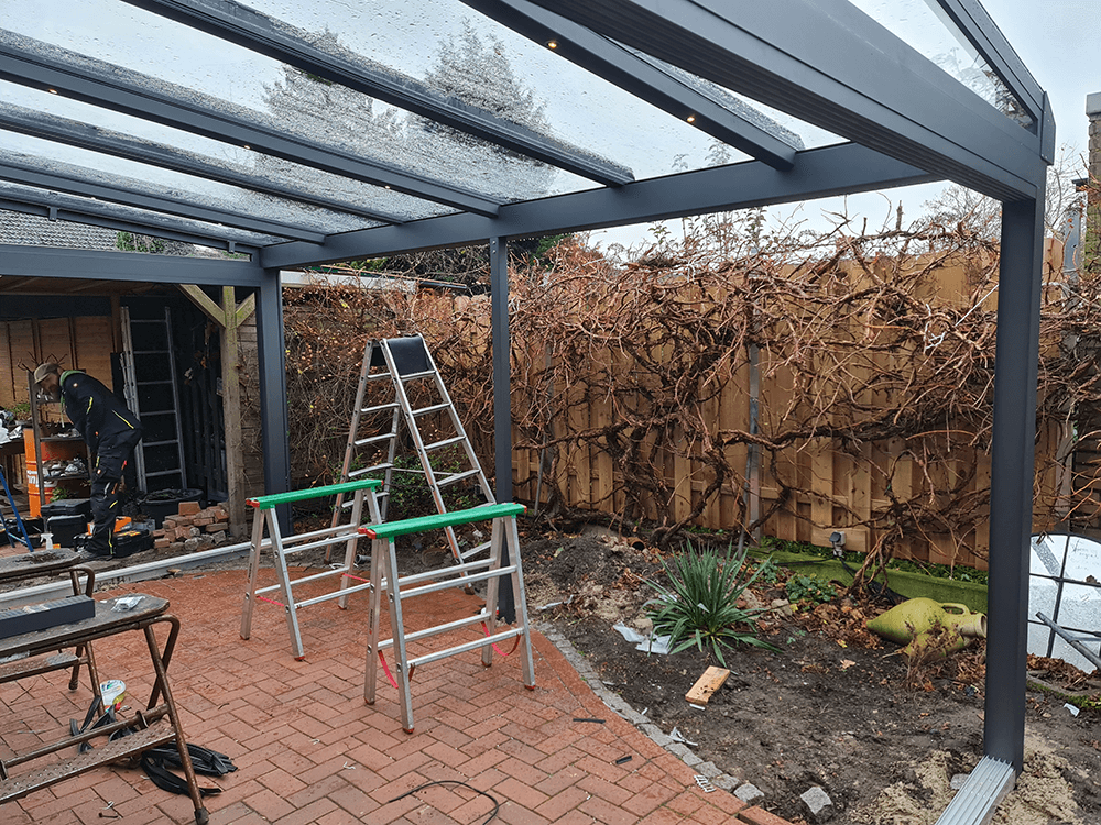 In einem Hinterhof steht unter einem Vordach eine Leiter.