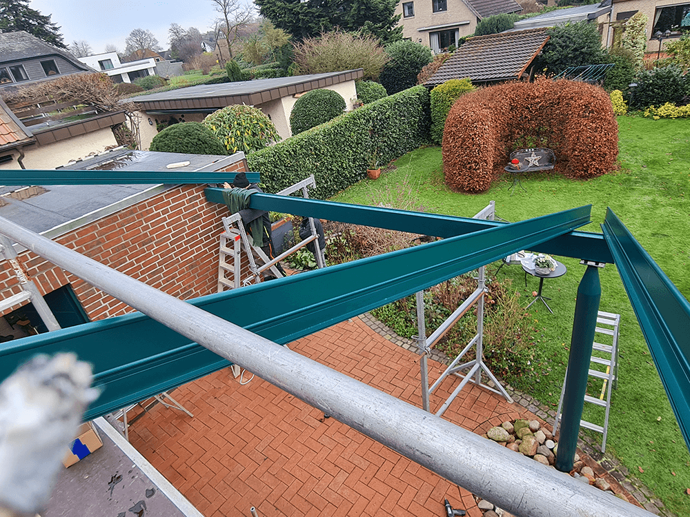 Eine Person steht auf einem Gerüst vor einem Haus.
