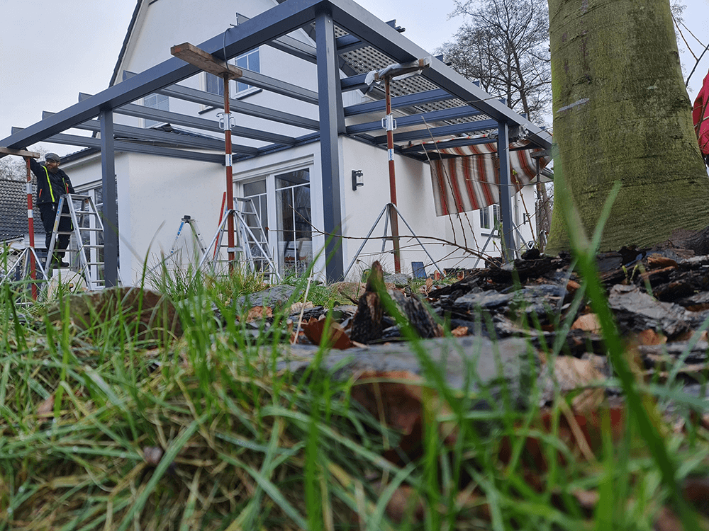 Ein Mann steht auf einer Leiter vor einem Haus.