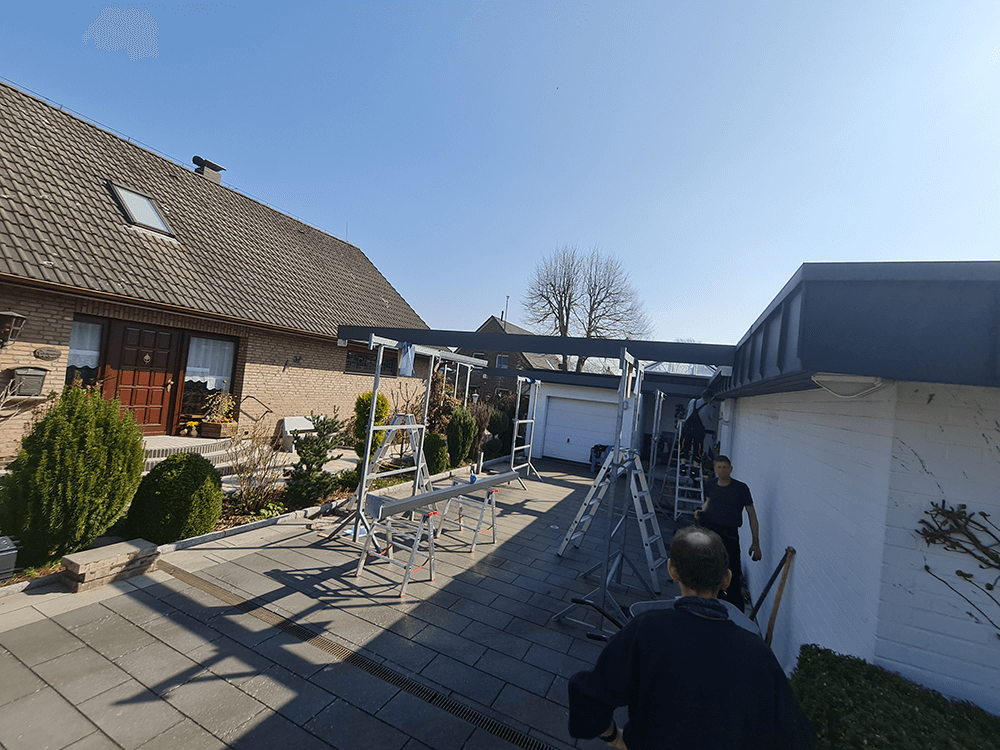 Ein Mann steht mit einer Leiter vor einem Haus.