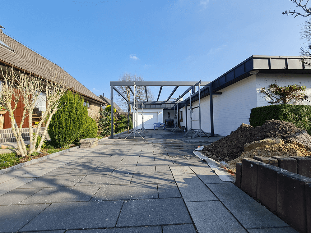 Vor einem Haus wird ein Carport gebaut.