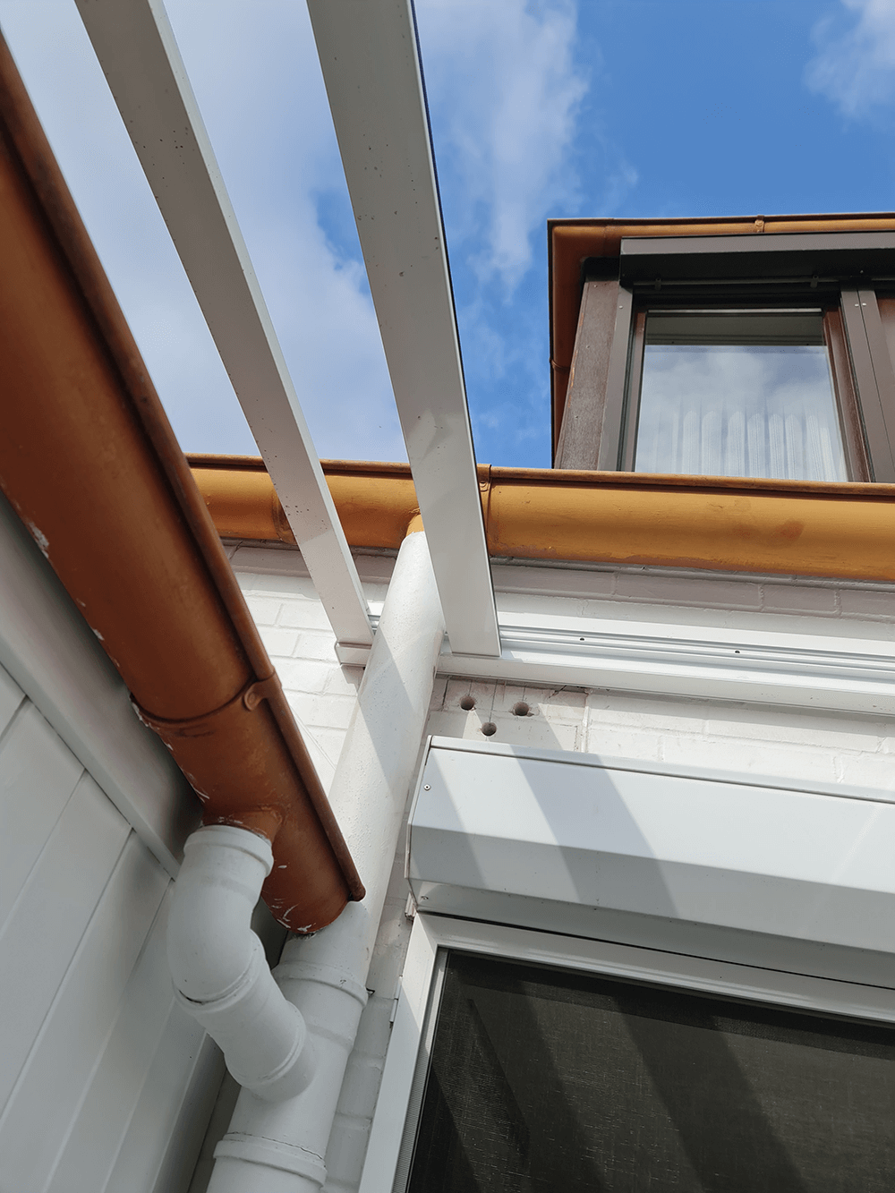 Blick nach oben auf das Dach eines Hauses mit einem Fenster