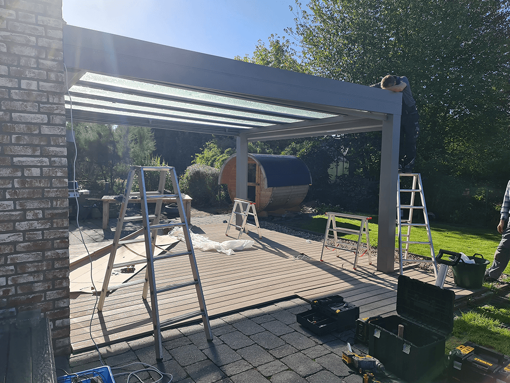 Ein Mann arbeitet in einem Hinterhof an einer Pergola.