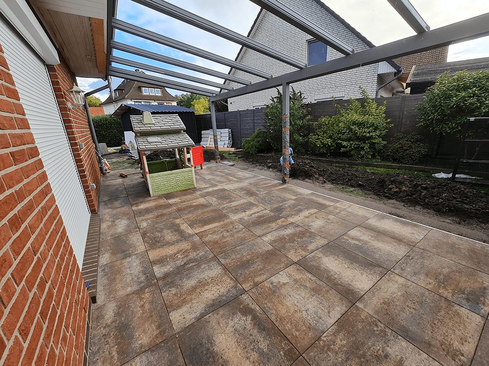 Ein Innenhof mit Pergola und im Hintergrund ein Backsteingebäude.