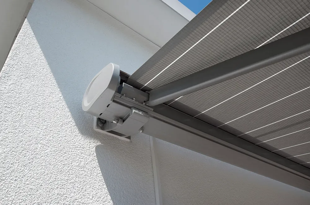 Eine Nahaufnahme einer grauen Markise an einer weißen Wand.