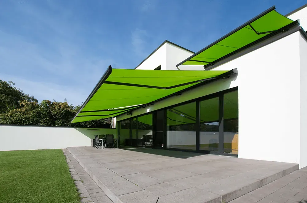 Ein weißes Haus mit einer grünen Markise über der Terrasse