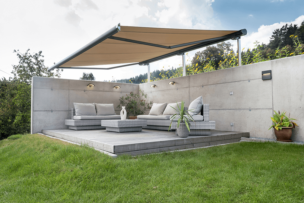 Eine Terrasse mit Couch und Tisch unter einer Markise.